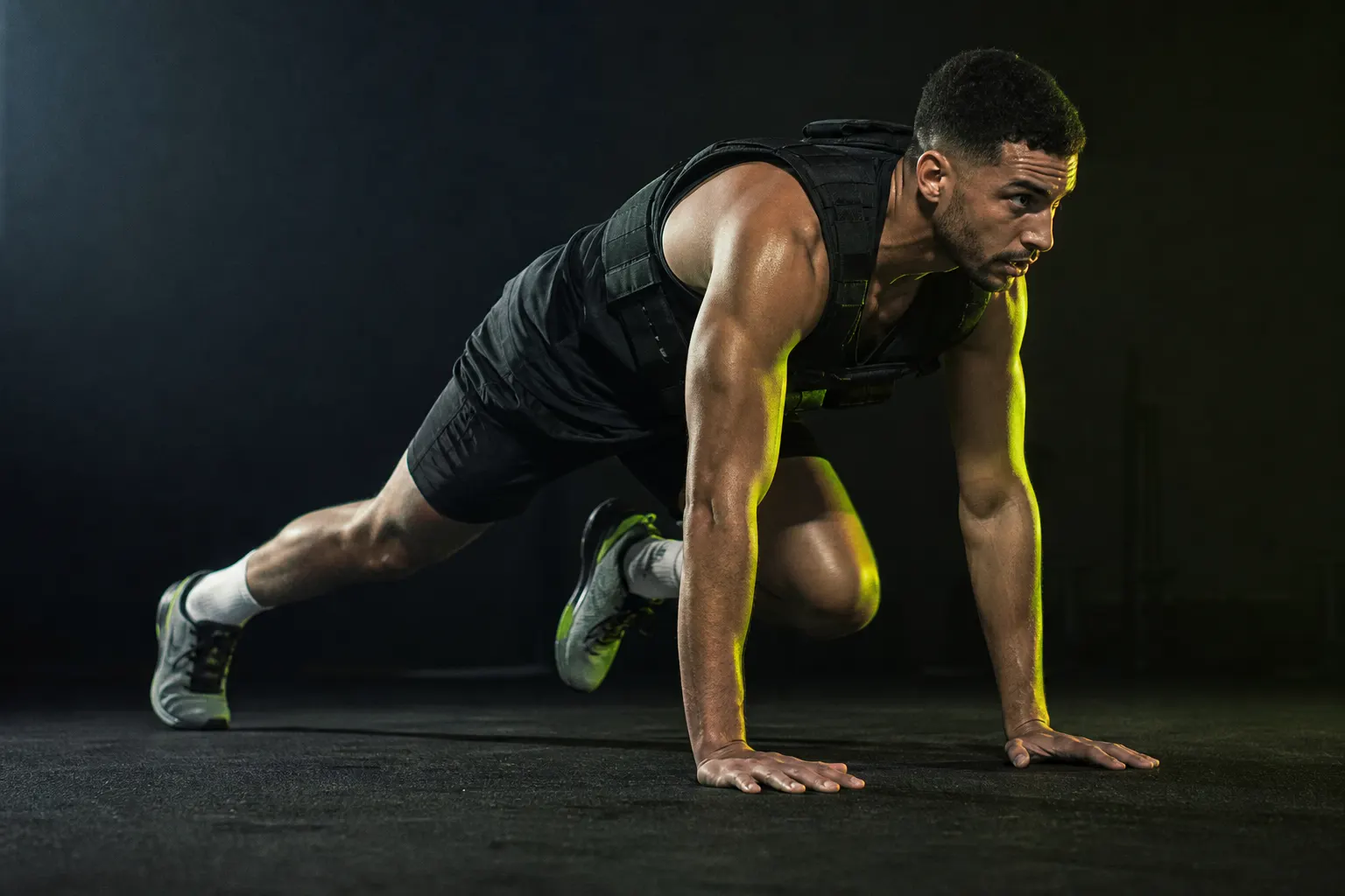 Sportif en effort HIIT intense avec gilet léger en studio sombre